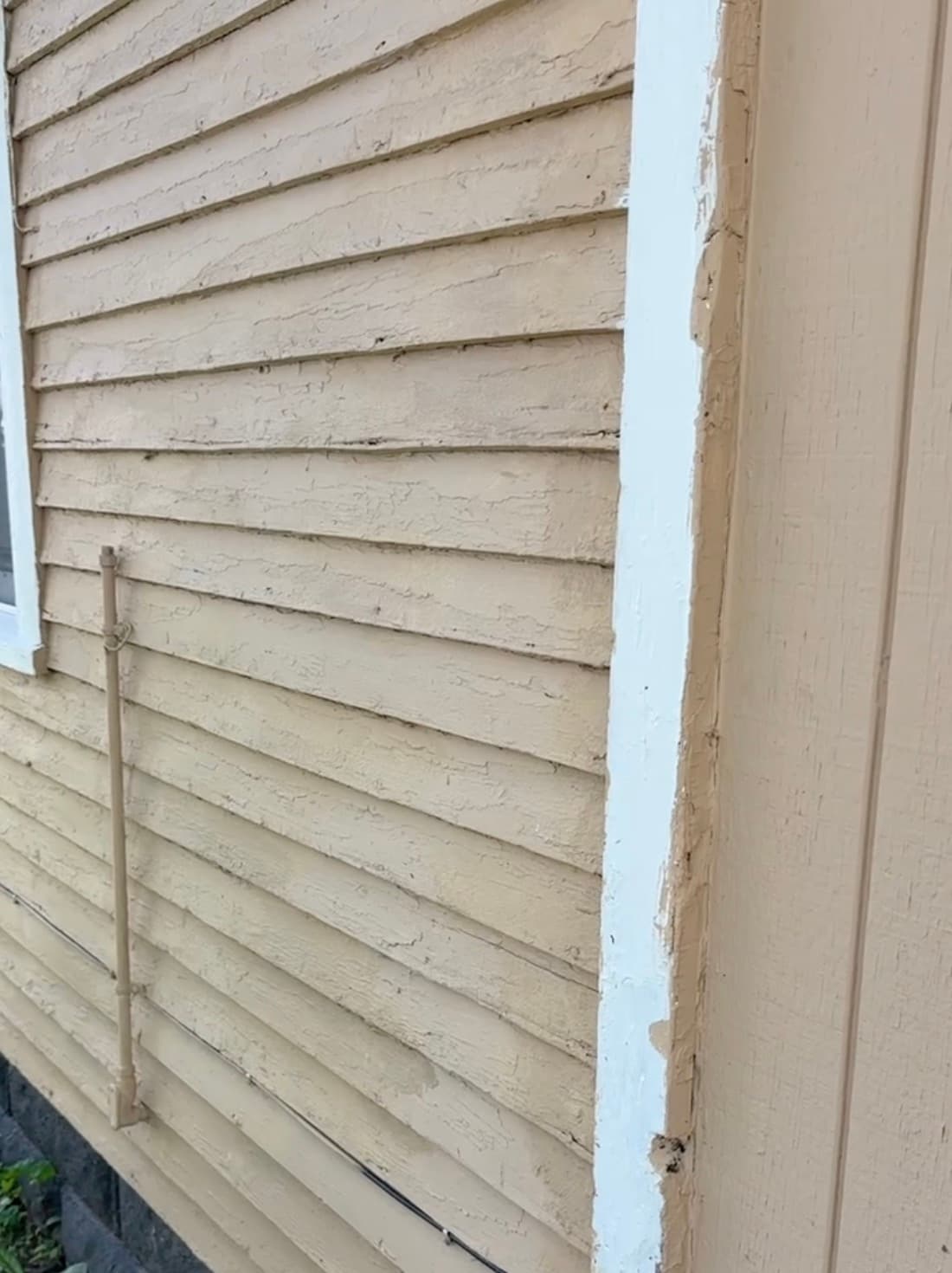 Scraping and repainting weathered exterior siding and trim