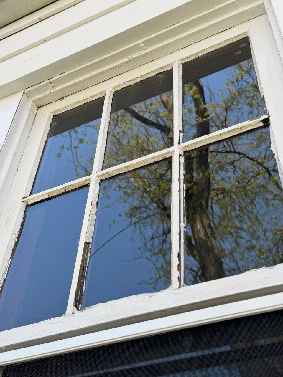 Old divided-light sash with failing glazing and a cracked pane
